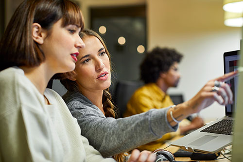 Two female workers looking at a computer screen